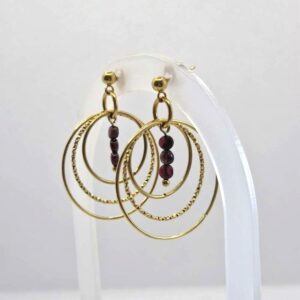 Clou d'oreilles doré avec plusieurs cercles et des grenats aux centre